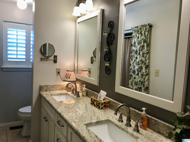 bathroom with tile patterned flooring, double vanity, toilet, and a sink