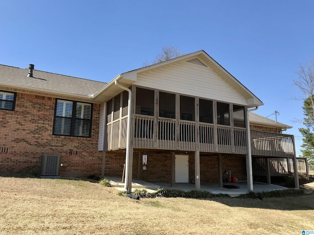 rear view of property with a patio, roof with shingles, a sunroom, central air condition unit, and brick siding