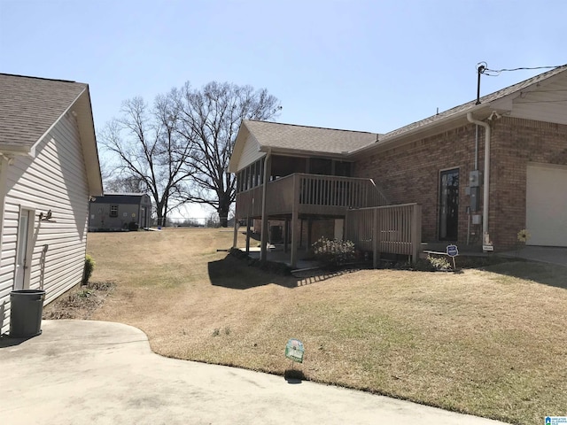 view of side of home with a yard, brick siding, and a shingled roof