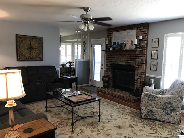 living area featuring a textured ceiling, a fireplace, and a ceiling fan