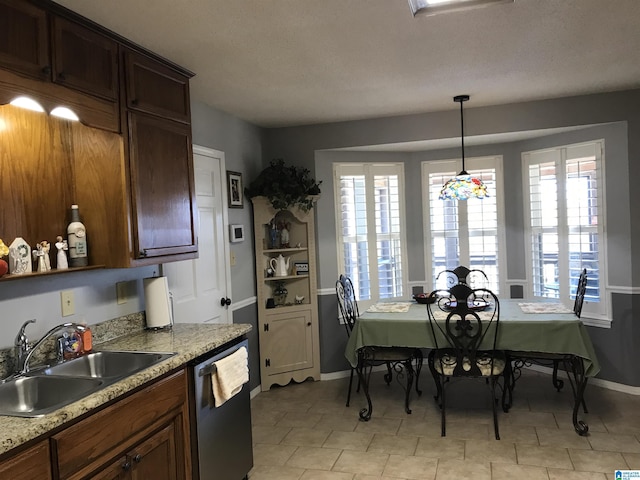 kitchen with decorative light fixtures, dishwasher, baseboards, and a sink