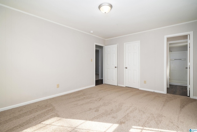 unfurnished bedroom featuring carpet flooring, crown molding, and baseboards