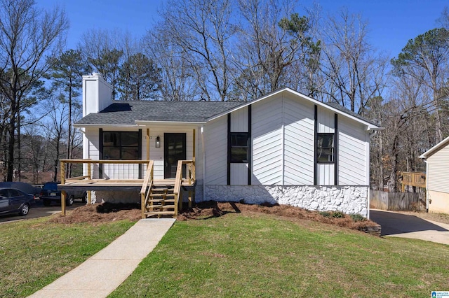 view of front of property featuring roof with shingles, a chimney, a front lawn, and a porch