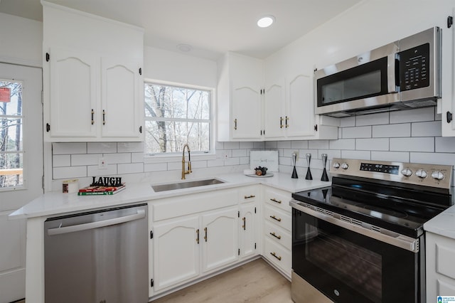 kitchen with white cabinets, tasteful backsplash, stainless steel appliances, and a sink