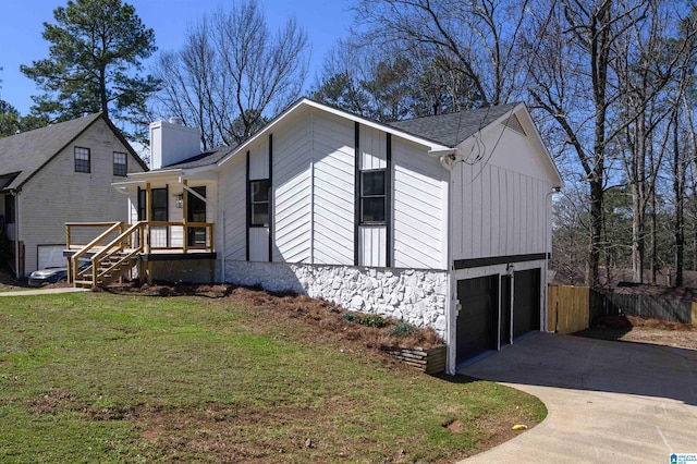 view of front of property with a garage, fence, driveway, a front lawn, and a chimney