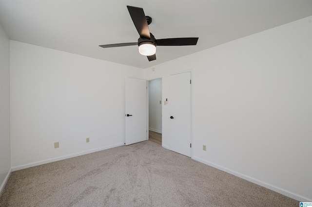 carpeted spare room featuring a ceiling fan and baseboards