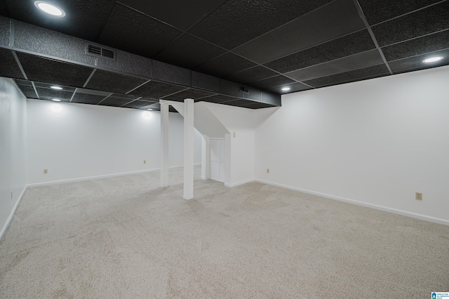 finished below grade area featuring carpet floors, a paneled ceiling, visible vents, and baseboards