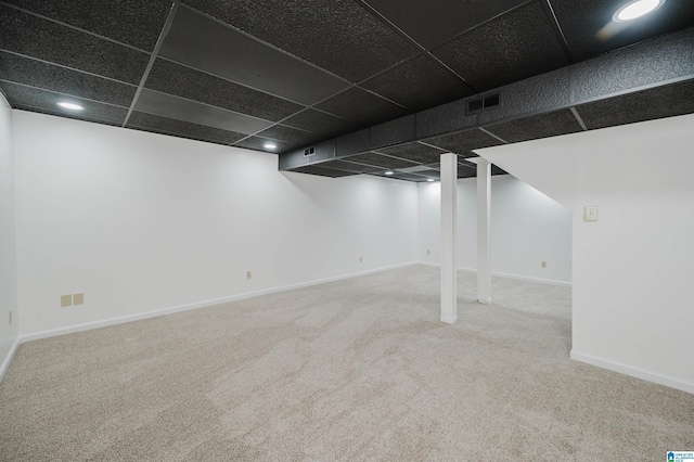 finished basement with carpet, visible vents, a drop ceiling, and baseboards