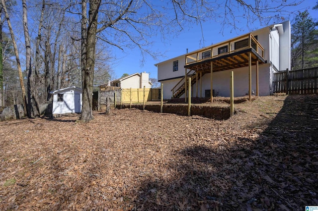 back of house featuring an outbuilding, a storage shed, fence, a wooden deck, and stairs