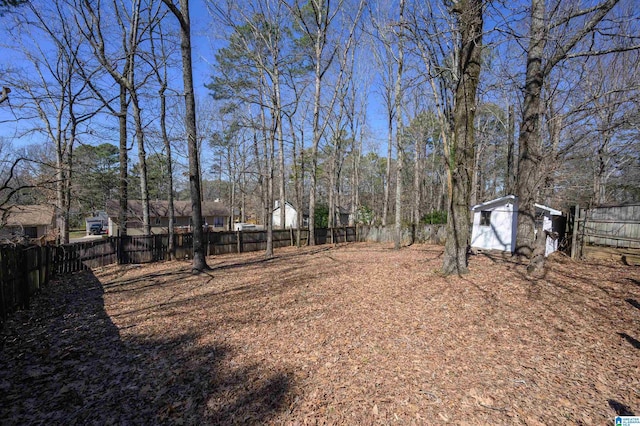 view of yard with a fenced backyard, a storage unit, and an outbuilding