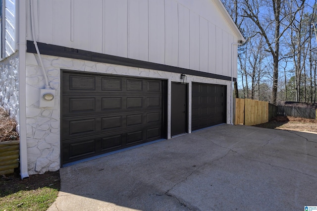 garage with fence and concrete driveway