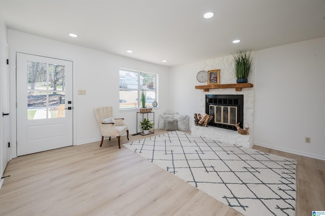 sitting room featuring baseboards, a stone fireplace, wood finished floors, and recessed lighting