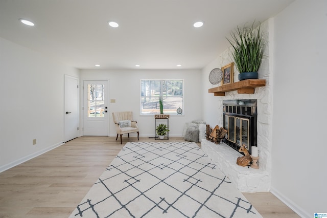 living area with light wood-type flooring, recessed lighting, and a stone fireplace