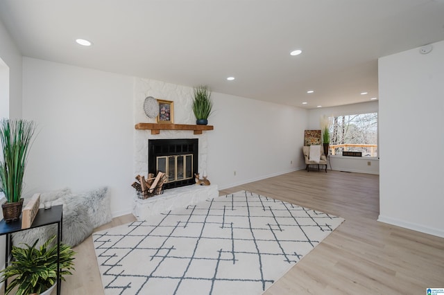 unfurnished living room with a large fireplace, baseboards, wood finished floors, and recessed lighting