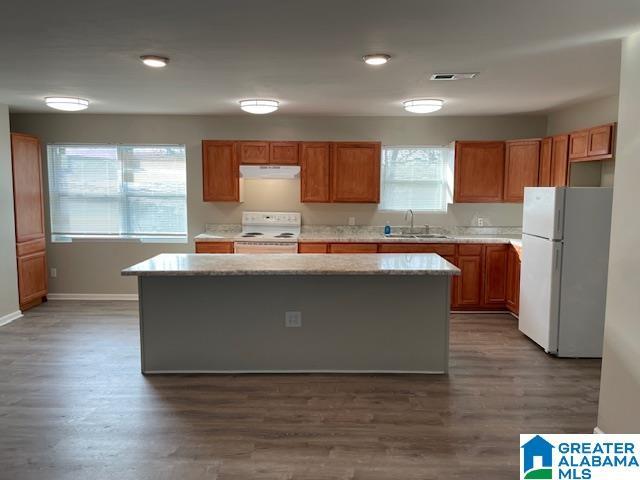 kitchen with extractor fan, white appliances, a kitchen island, a sink, and dark wood-style floors