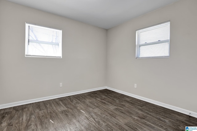 unfurnished room featuring baseboards and dark wood-style flooring