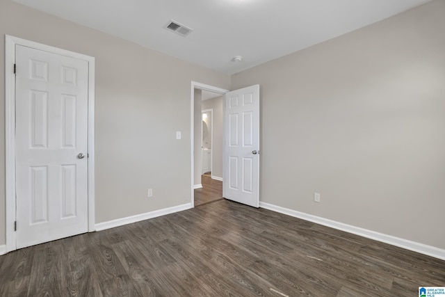 unfurnished bedroom featuring baseboards, visible vents, and dark wood finished floors