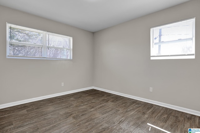 spare room with dark wood-type flooring and baseboards