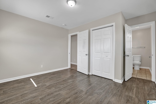 unfurnished bedroom with a closet, visible vents, baseboards, and wood finished floors