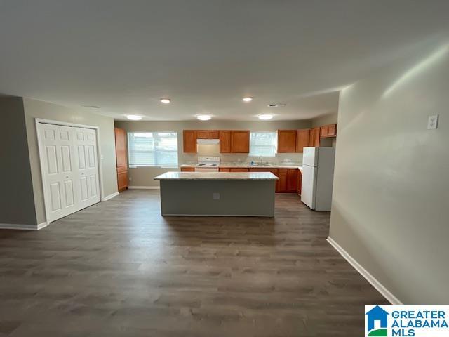 kitchen featuring a kitchen island, baseboards, light countertops, and freestanding refrigerator