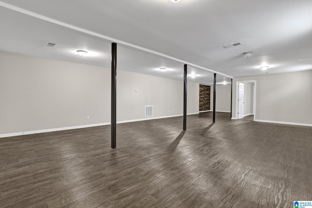 finished below grade area featuring baseboards, visible vents, and dark wood-type flooring