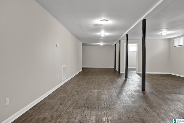 below grade area featuring baseboards, visible vents, and dark wood finished floors