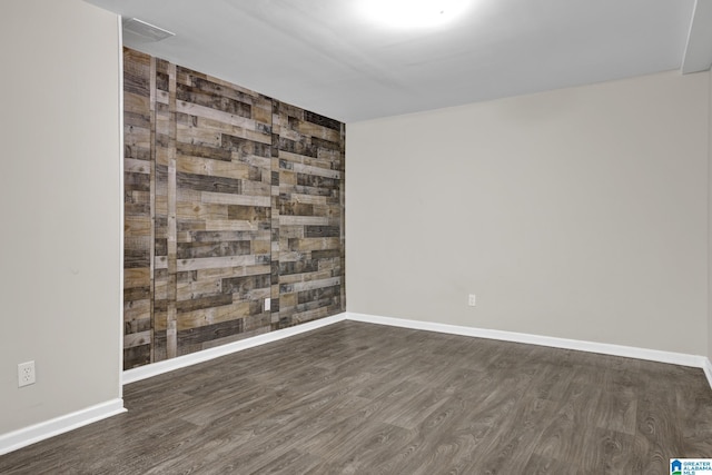 unfurnished room with an accent wall, baseboards, and wood finished floors