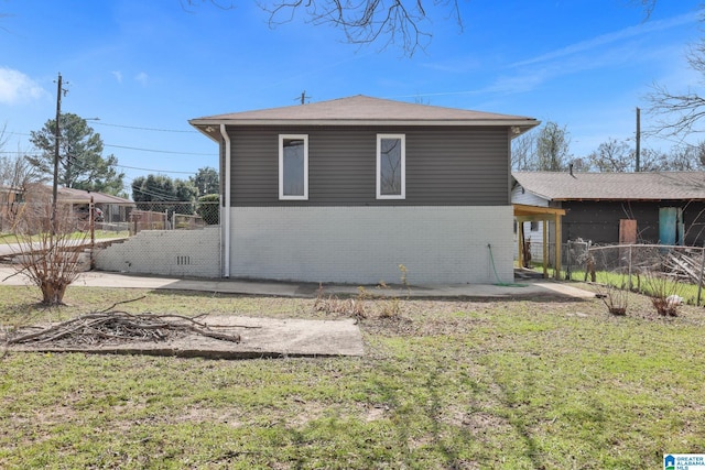 rear view of property with brick siding, fence, a patio, and a lawn