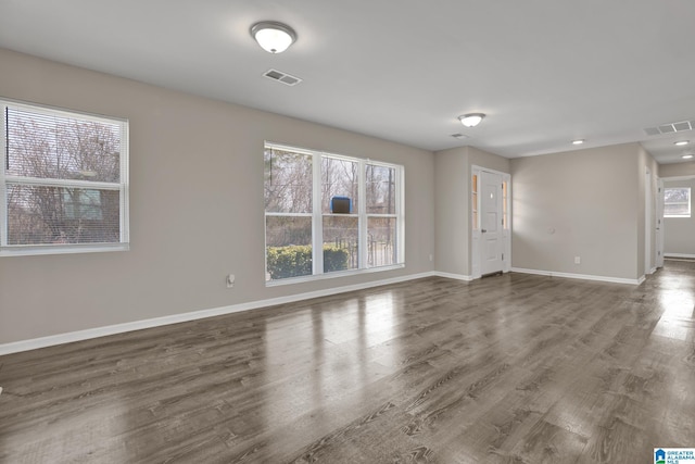 unfurnished room with baseboards, visible vents, and wood finished floors