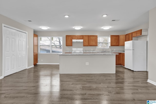 kitchen with under cabinet range hood, range with electric cooktop, visible vents, light countertops, and freestanding refrigerator