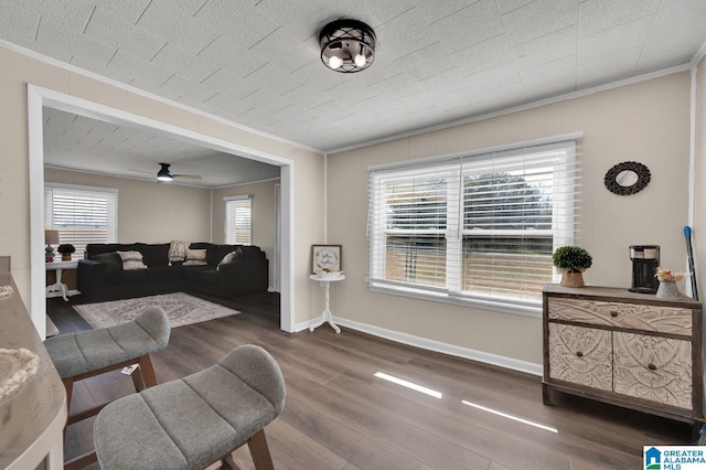 living area with baseboards, crown molding, and wood finished floors