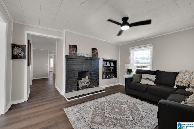 living room with baseboards, dark wood finished floors, a ceiling fan, ornamental molding, and a brick fireplace