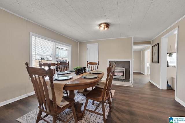 dining area with baseboards, dark wood-type flooring, heating unit, crown molding, and a fireplace