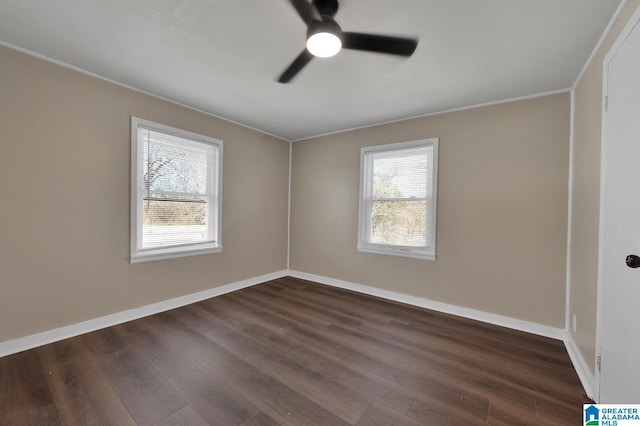 unfurnished room featuring dark wood-style floors, a wealth of natural light, and baseboards