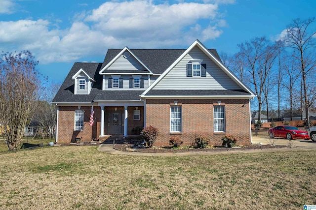 view of front of property featuring brick siding, roof with shingles, and a front yard