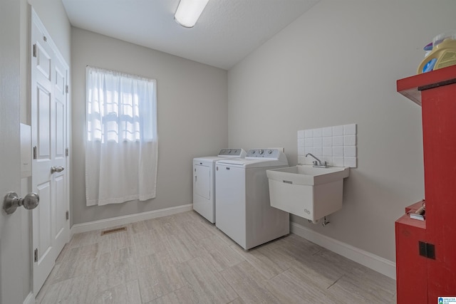 clothes washing area with laundry area, baseboards, visible vents, independent washer and dryer, and a sink