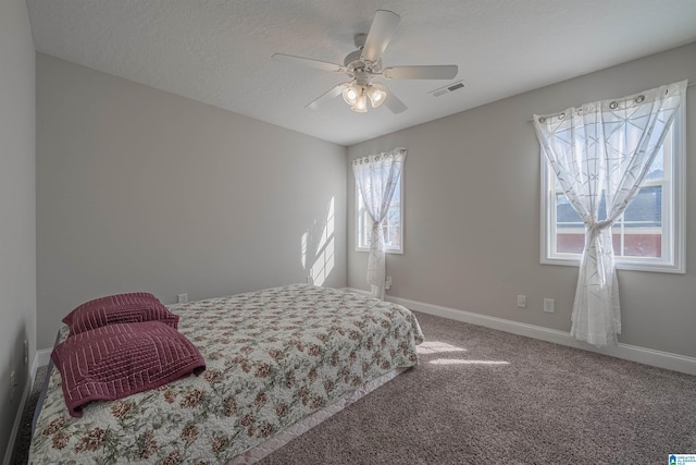 bedroom with a textured ceiling, a ceiling fan, visible vents, baseboards, and carpet