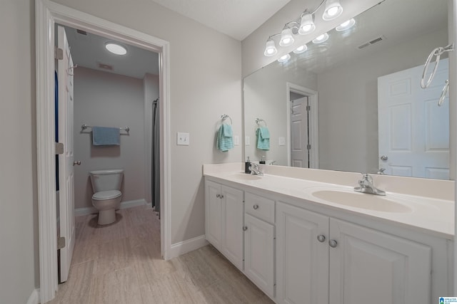 full bathroom with toilet, double vanity, visible vents, and a sink