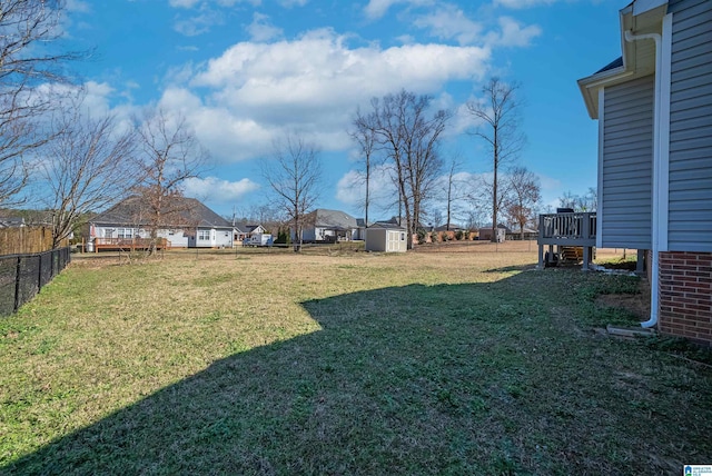 view of yard featuring a storage shed, fence, and an outbuilding