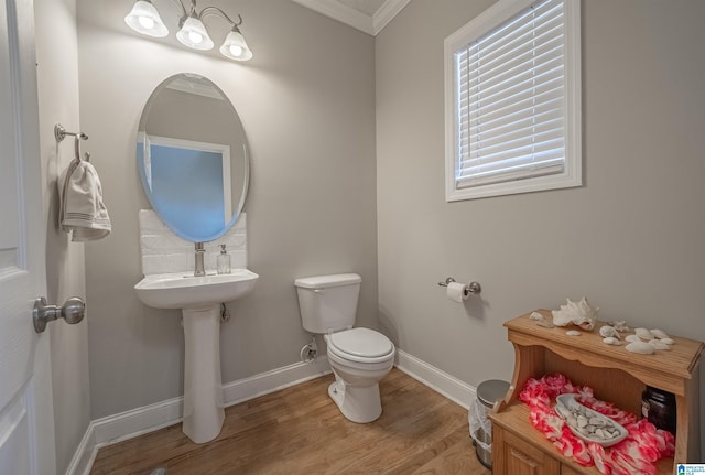 bathroom with toilet, a sink, wood finished floors, baseboards, and crown molding