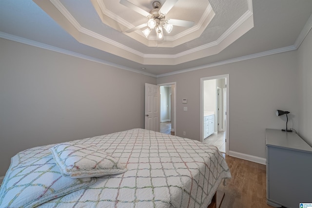 bedroom with a raised ceiling, a ceiling fan, ornamental molding, wood finished floors, and baseboards