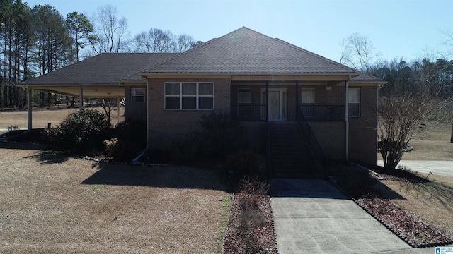 view of front of house with driveway, a porch, roof with shingles, and brick siding