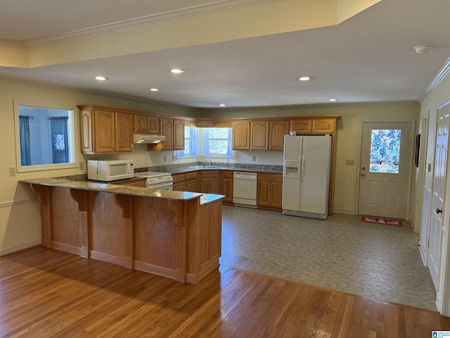 kitchen featuring white appliances, brown cabinets, a peninsula, under cabinet range hood, and a sink