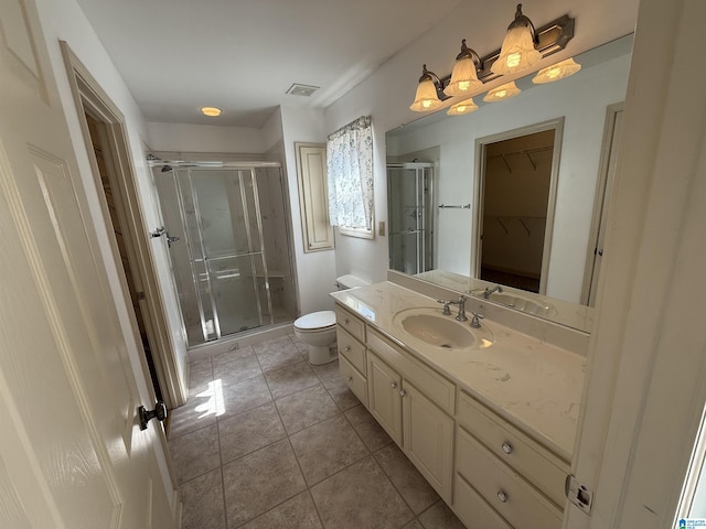 bathroom featuring toilet, vanity, visible vents, a shower stall, and tile patterned floors