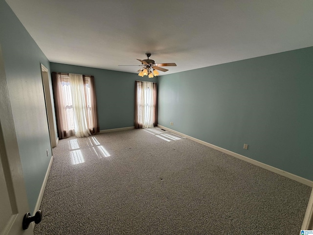 carpeted empty room featuring baseboards and a ceiling fan