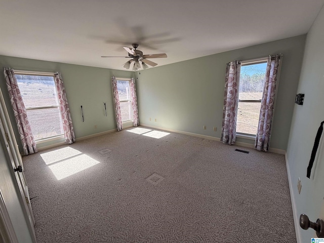 unfurnished room with a ceiling fan, carpet flooring, visible vents, and baseboards