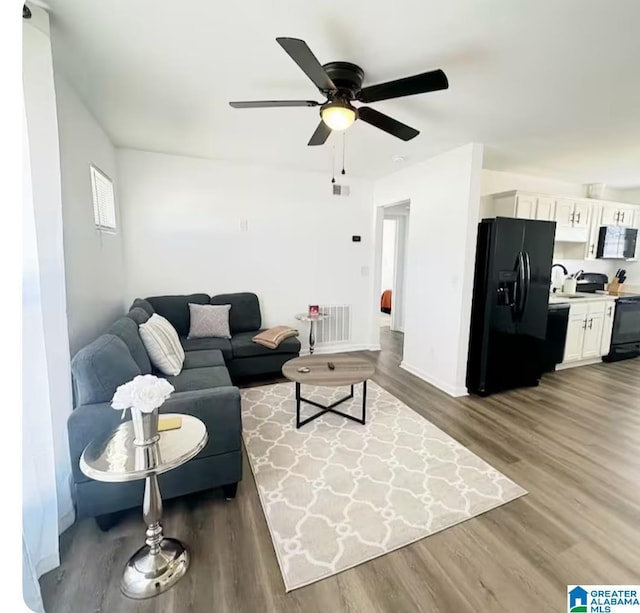 living area featuring baseboards, ceiling fan, visible vents, and wood finished floors