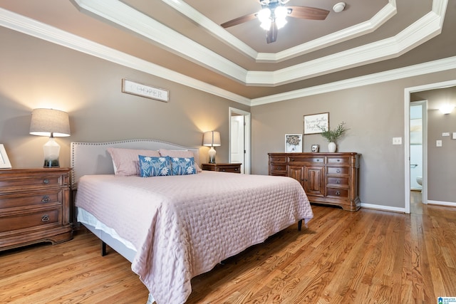 bedroom with ceiling fan, baseboards, ornamental molding, light wood-type flooring, and a raised ceiling