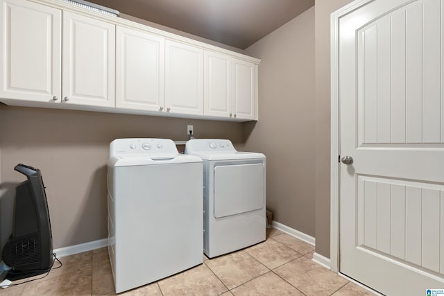 laundry area with light tile patterned floors, independent washer and dryer, cabinet space, and baseboards