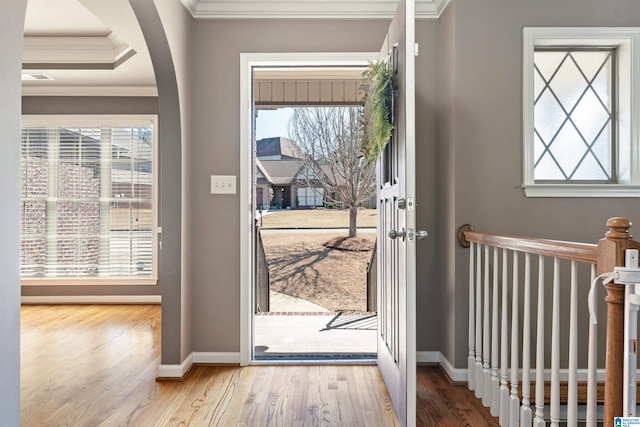 doorway to outside featuring a wealth of natural light, arched walkways, crown molding, and wood finished floors